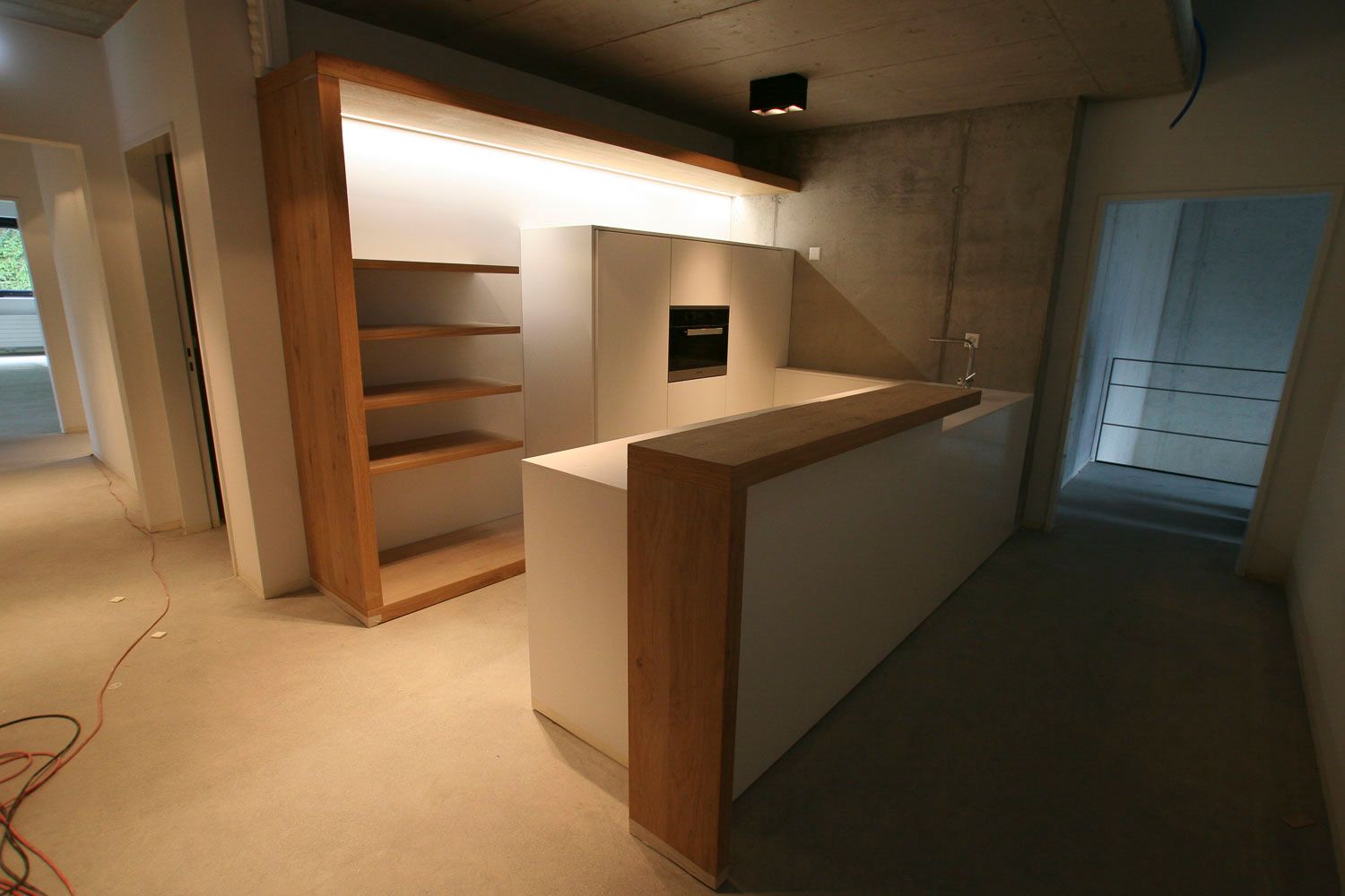 Eine Küche mit weißer Arbeitsplatte und Holzregalen