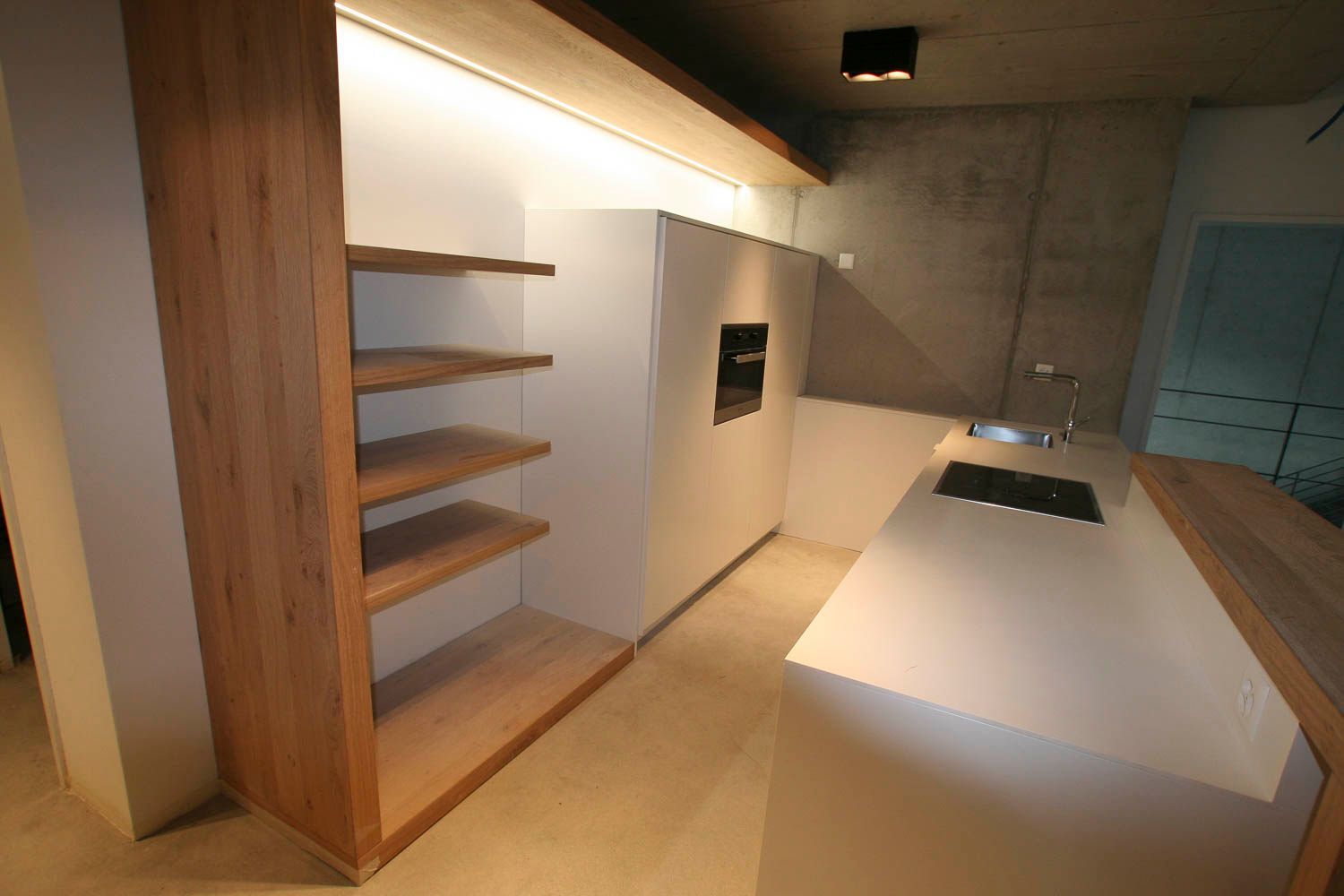 Eine Küche mit weißen Schränken und Holzregalen und einer Spüle.