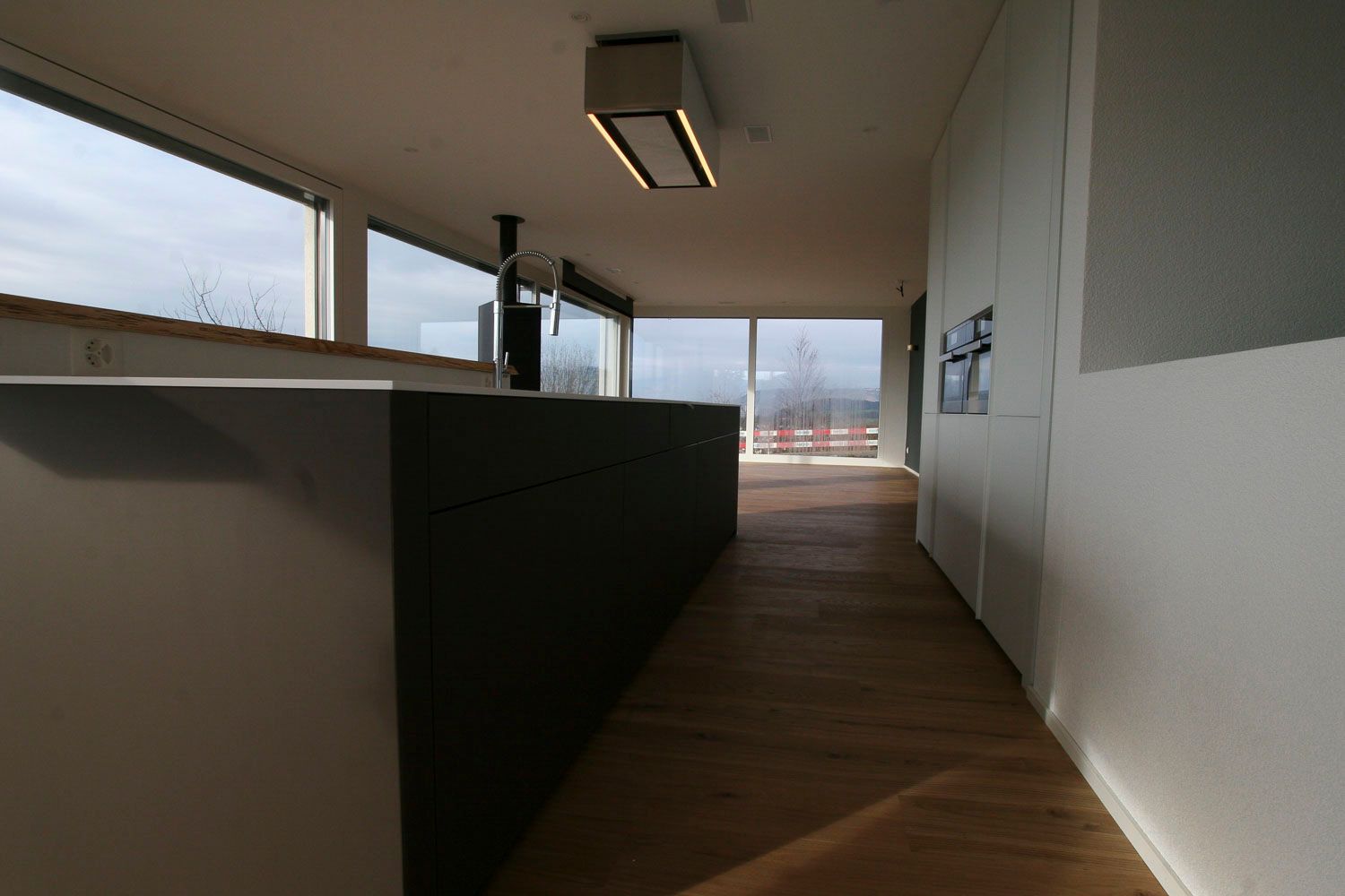 Ein langer Flur, der zu einer Küche mit vielen Fenstern führt