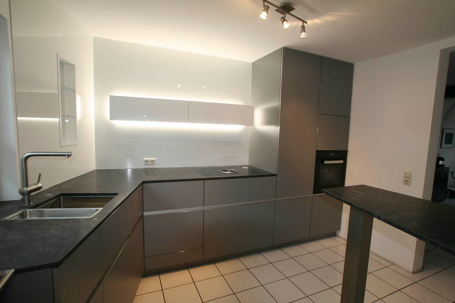 Eine Küche mit grauen Schränken und schwarzen Arbeitsplatten