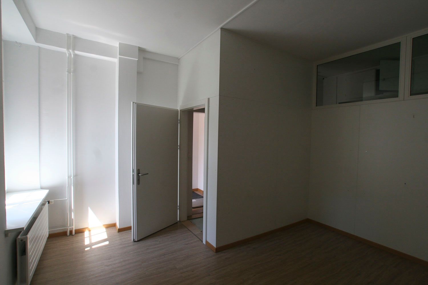 Ein leerer Raum mit zwei Türen und einem Fenster.