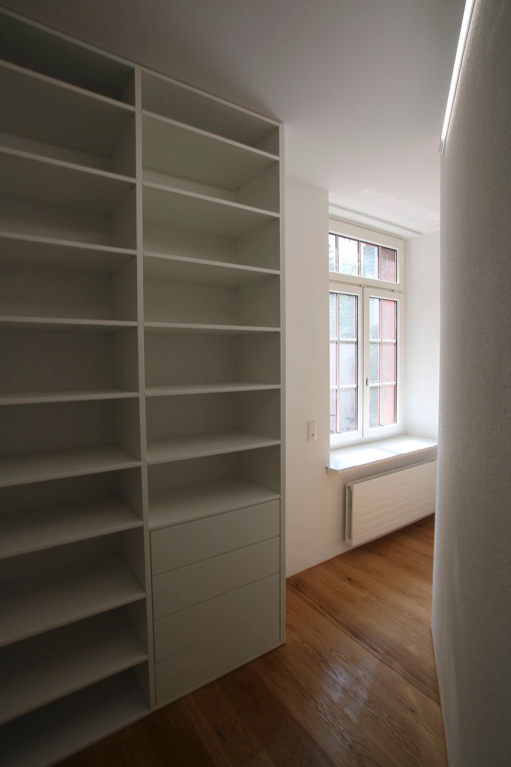 Ein Raum mit weißen Regalen und einem Fenster