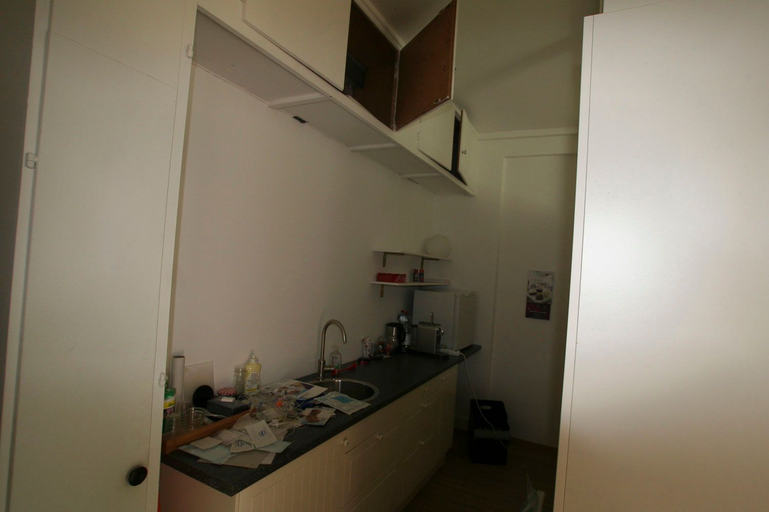 Eine Küche mit Spüle, Schränken und einer Tür.