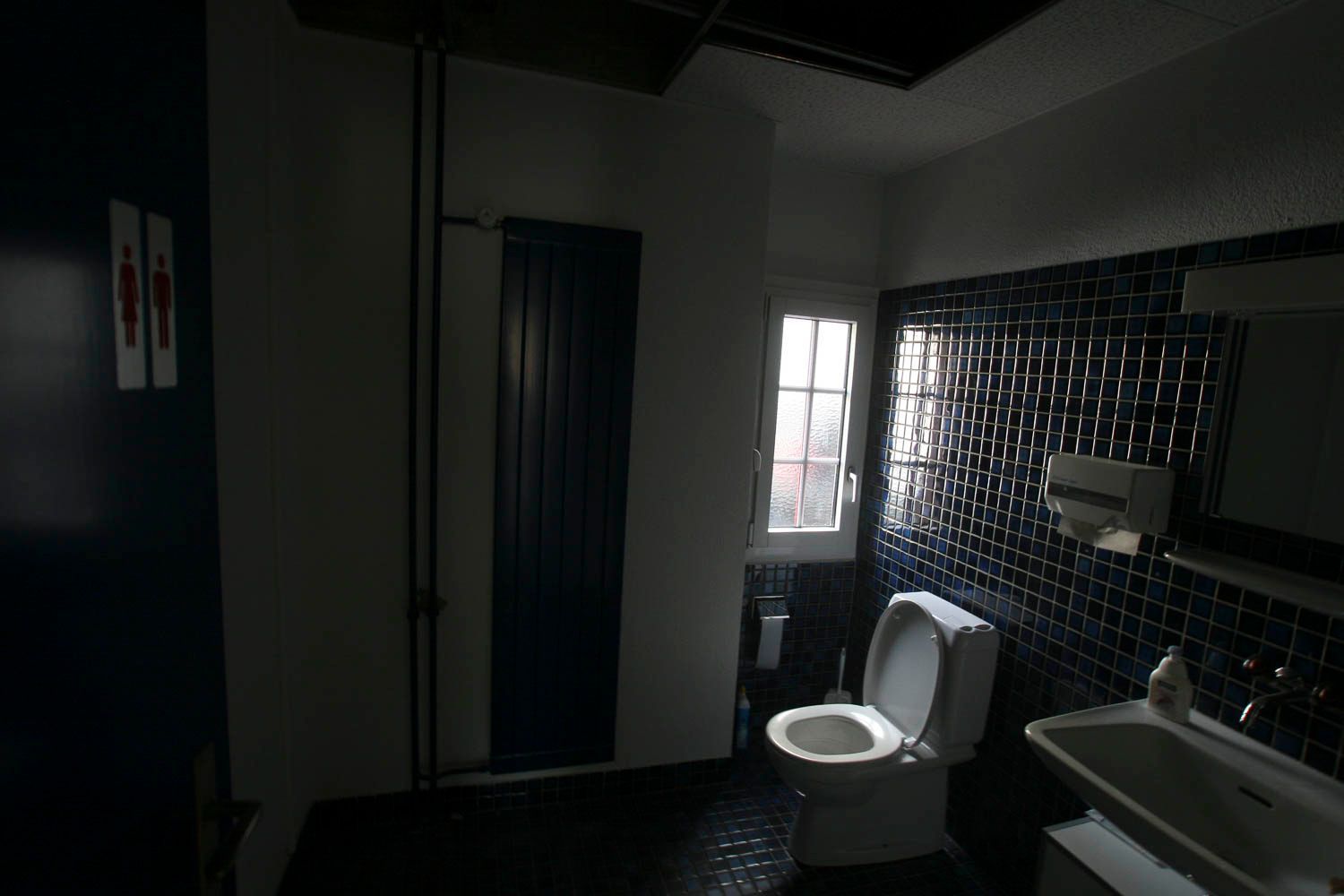 Ein dunkles Badezimmer mit Toilette und Waschbecken