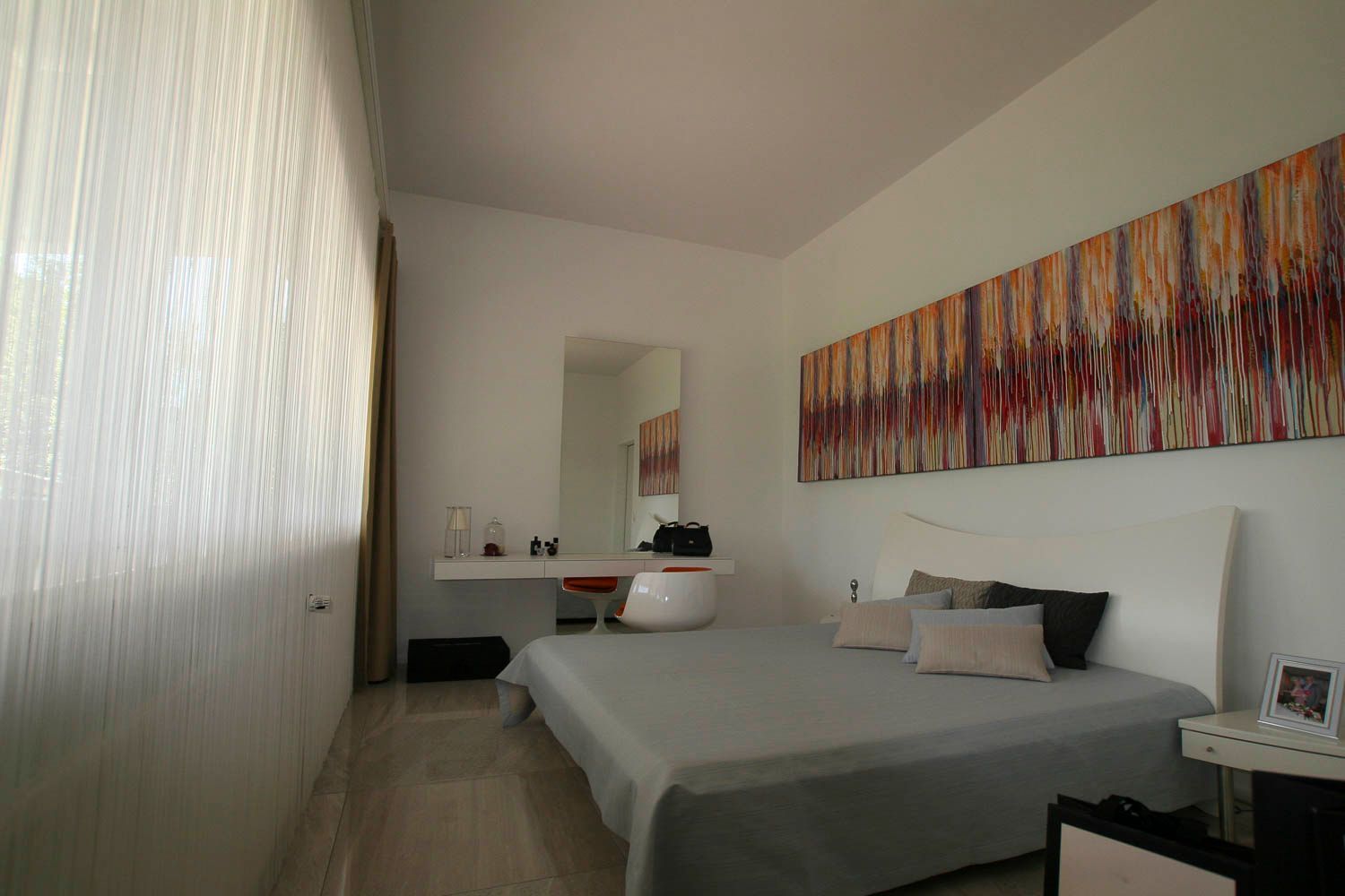 Ein Schlafzimmer mit einem großen Bett und einem Gemälde an der Wand.