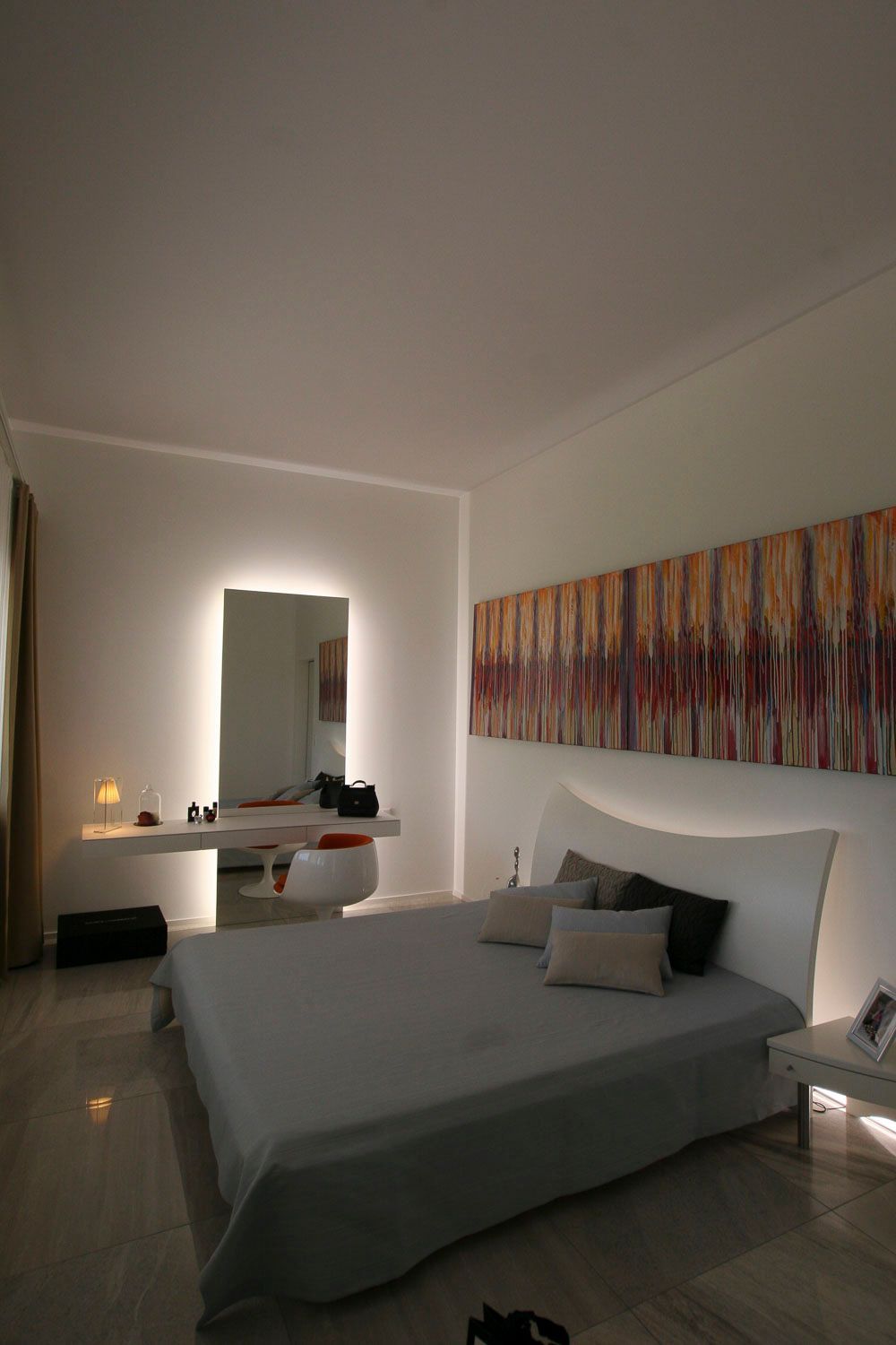 Ein Schlafzimmer mit einem Bett, einem Spiegel und einem Gemälde an der Wand