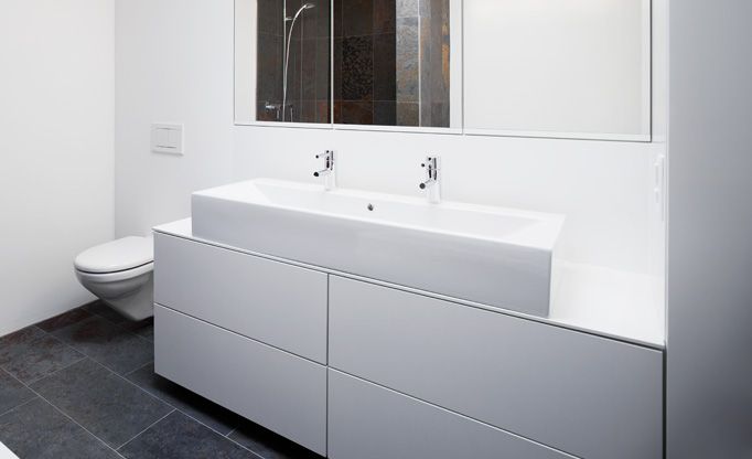 Ein Badezimmer mit zwei Waschbecken, einer Toilette und einem Spiegel.