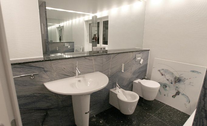 Ein Badezimmer mit zwei Toiletten, einem Waschbecken und einem Spiegel.