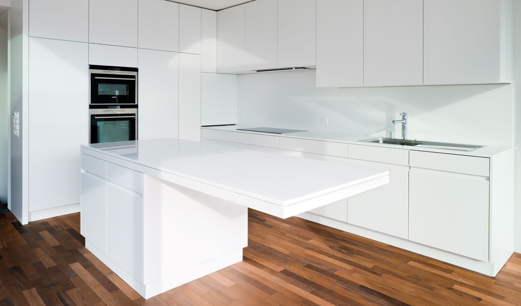 Eine Küche mit weißen Schränken und einem Holzboden