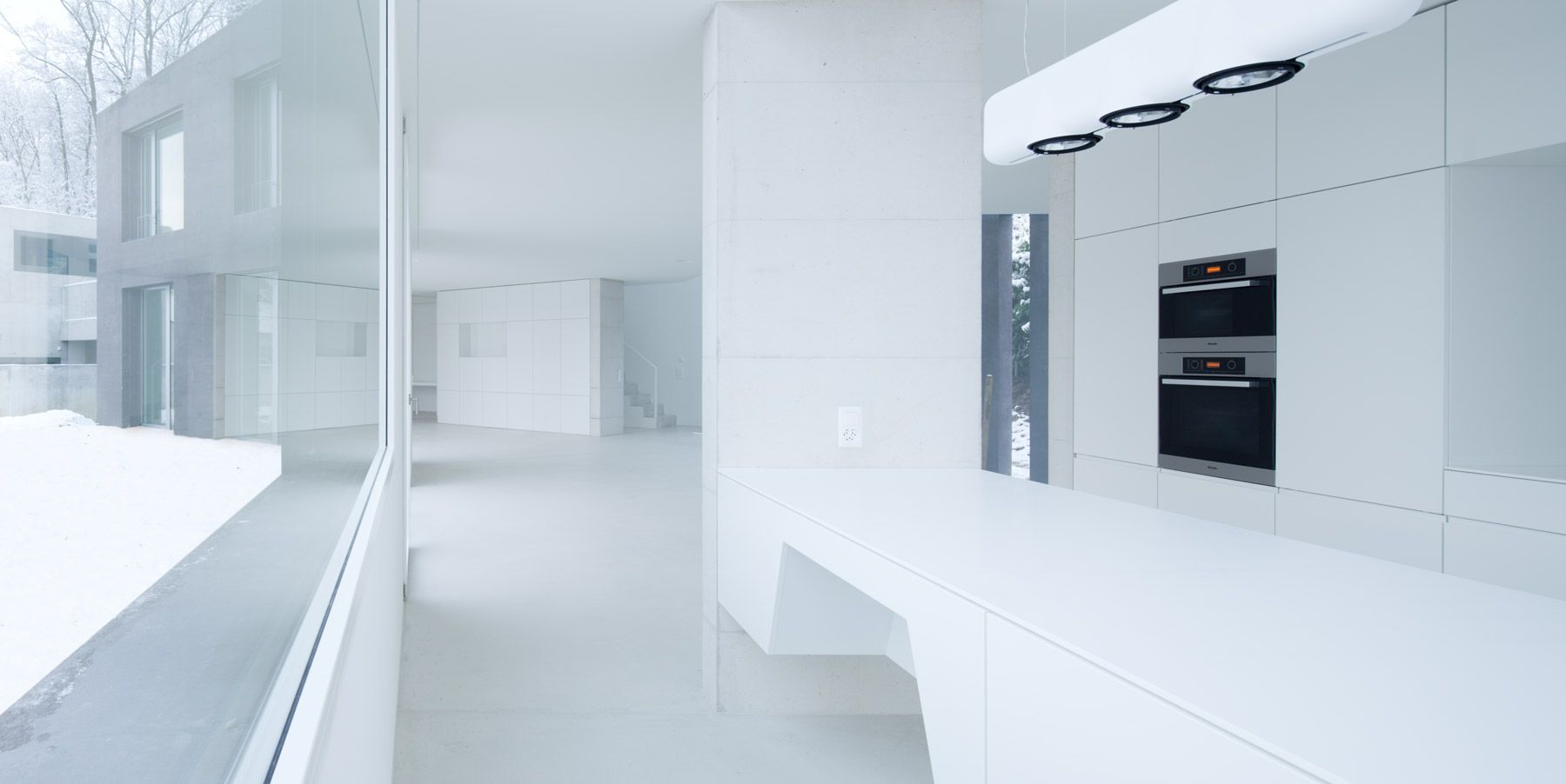 Eine leere Küche mit weißen Schränken und einem großen Fenster.