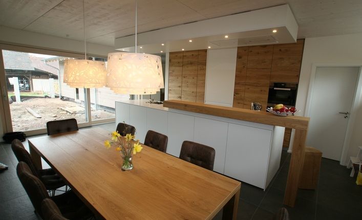 Ein Holztisch mit einer Blumenvase darauf in einer Küche.