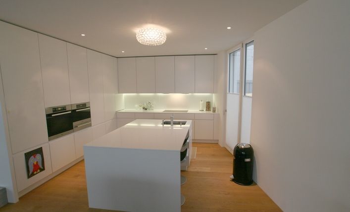 Eine Küche mit weißen Schränken und einer großen Insel in der Mitte.