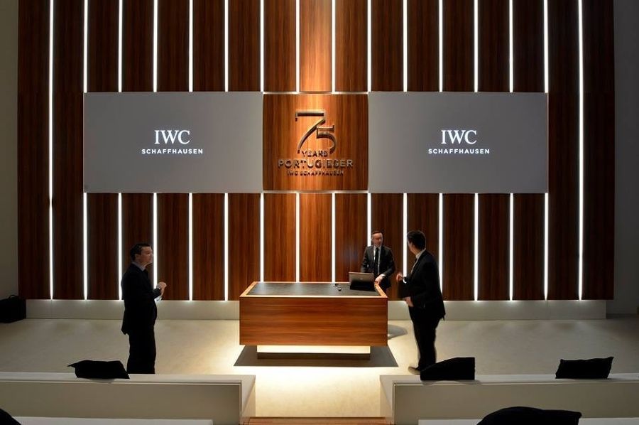 Zwei Männer stehen vor einer Holzwand mit der Aufschrift „iwc“
