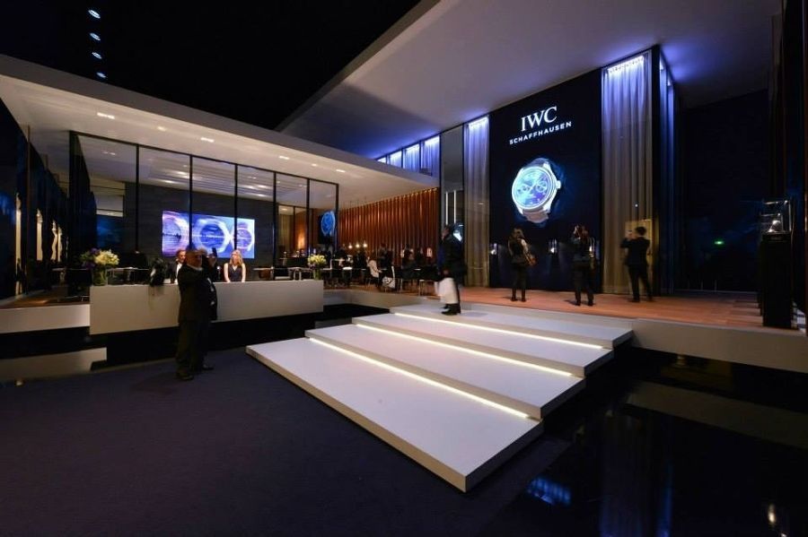 Eine Gruppe von Menschen steht auf einer Bühne vor einem großen IWC-Schild.