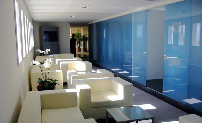 Ein langer Flur mit weißen Stühlen und blauen Wänden