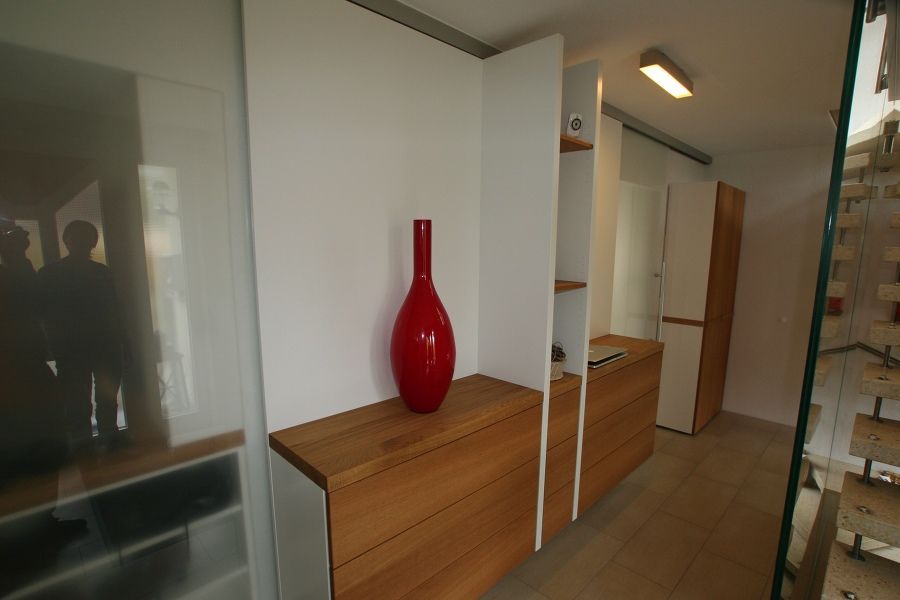 Eine rote Vase steht auf einem Holzregal in einem Raum