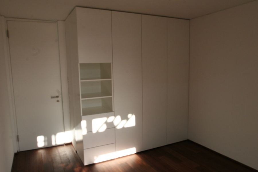 Ein Raum mit weißen Wänden und Regalen und einer Tür