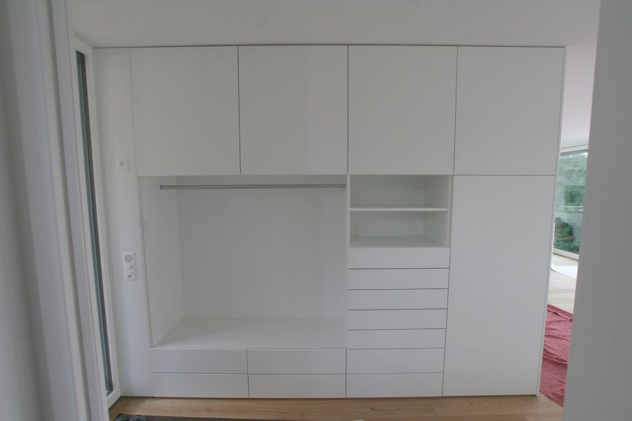 Ein weißer Kleiderschrank mit Schubladen und Regalen in einem Zimmer.