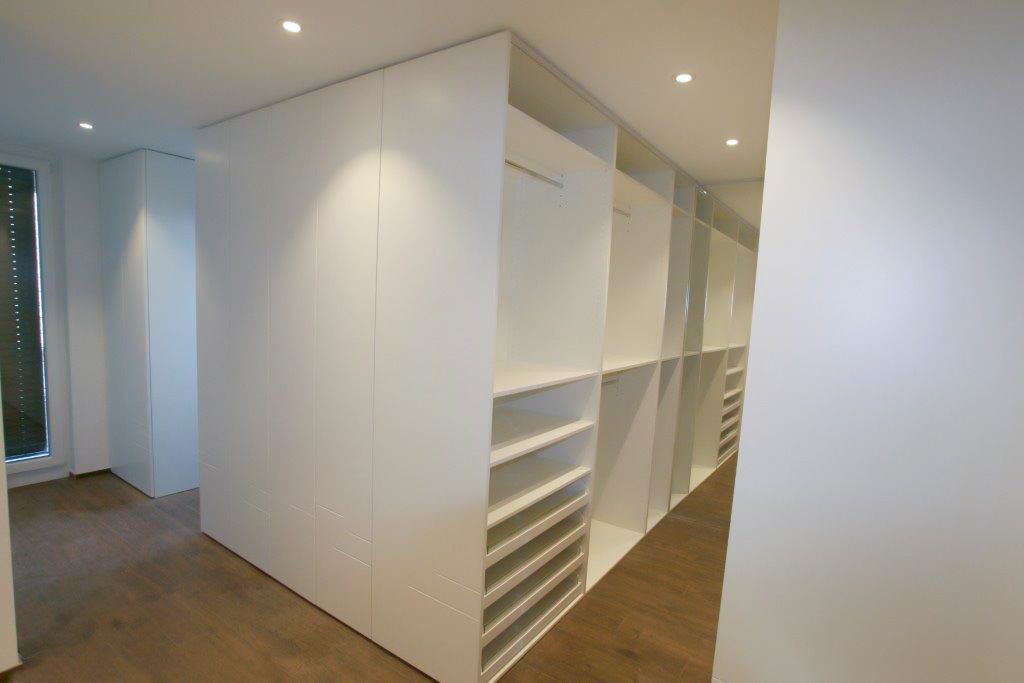 Ein begehbarer Kleiderschrank mit vielen Regalen und einem Fenster.