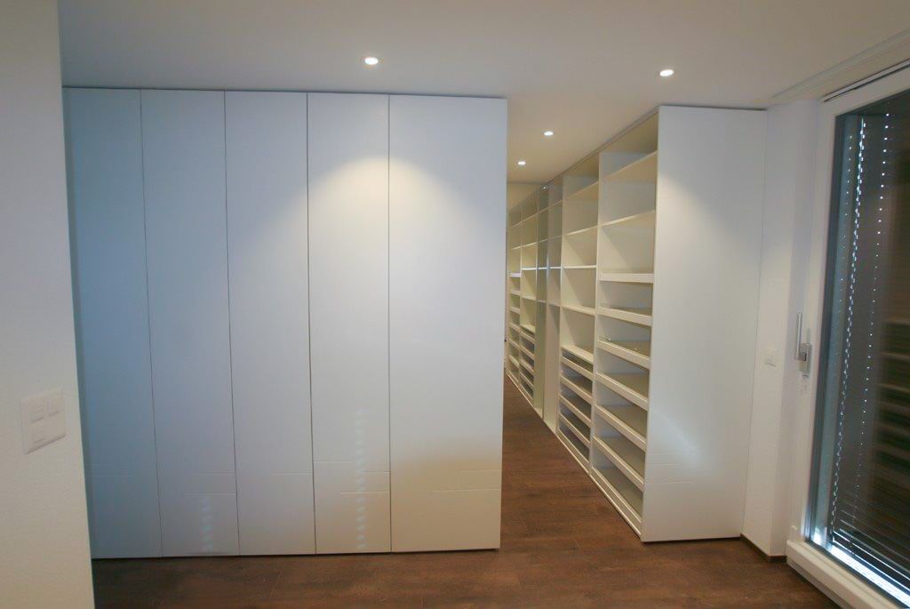 Ein begehbarer Kleiderschrank mit vielen Regalen und einem Fenster