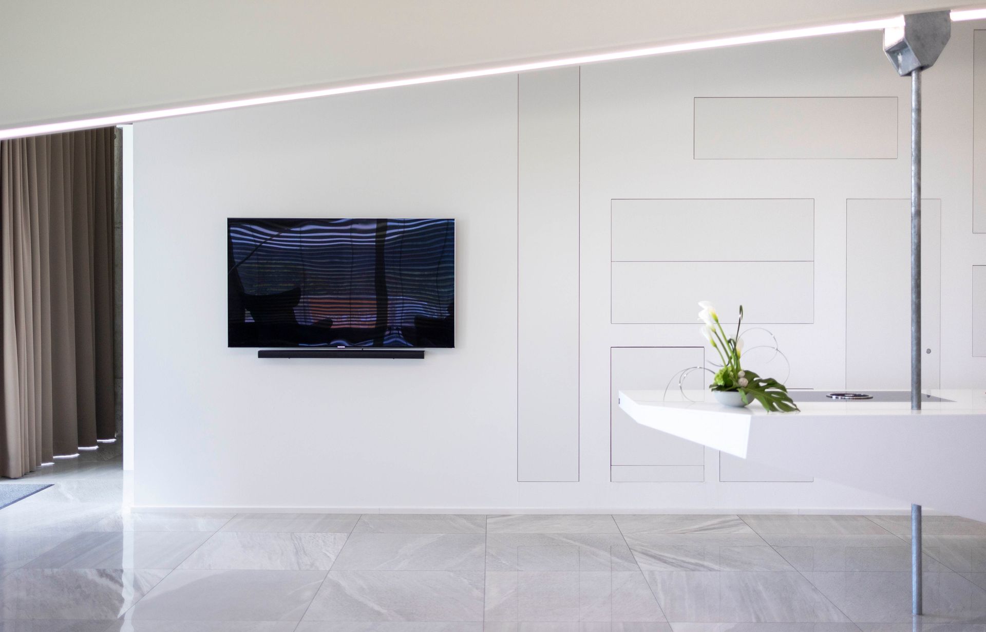 Ein Wohnzimmer mit einem Flachbildfernseher an der Wand.