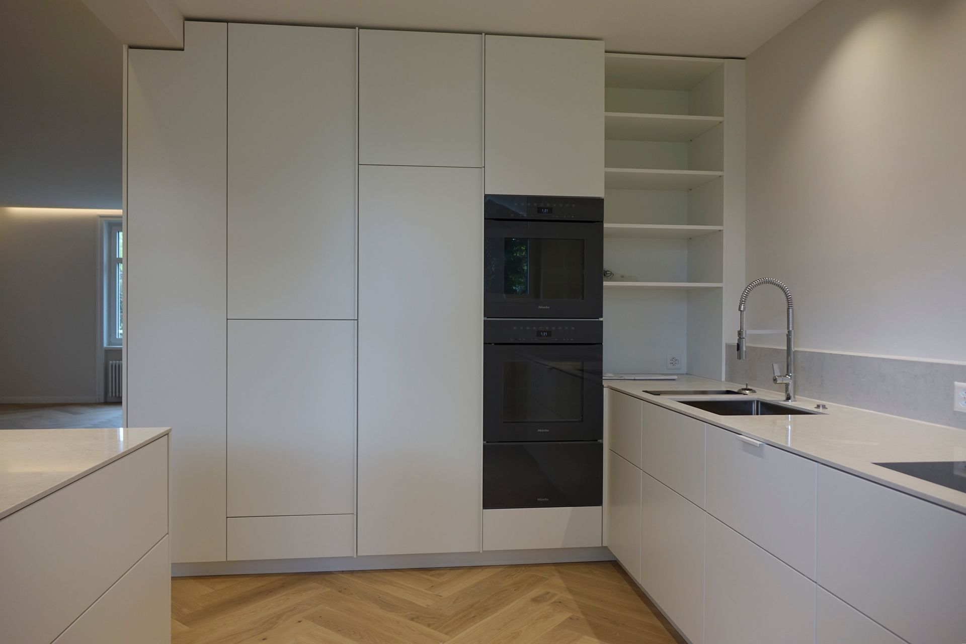 Eine Küche mit weißen Schränken und Holzboden.