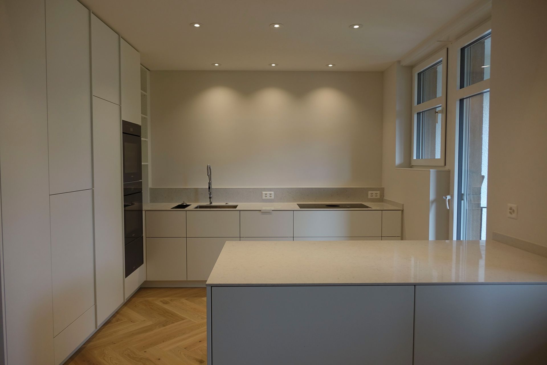 Eine leere Küche mit weißen Schränken und einer großen Kochinsel.