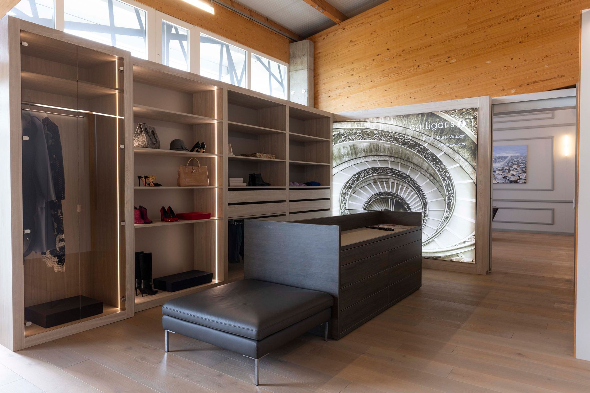 Ein großer begehbarer Kleiderschrank mit vielen Regalen und einer Bank.