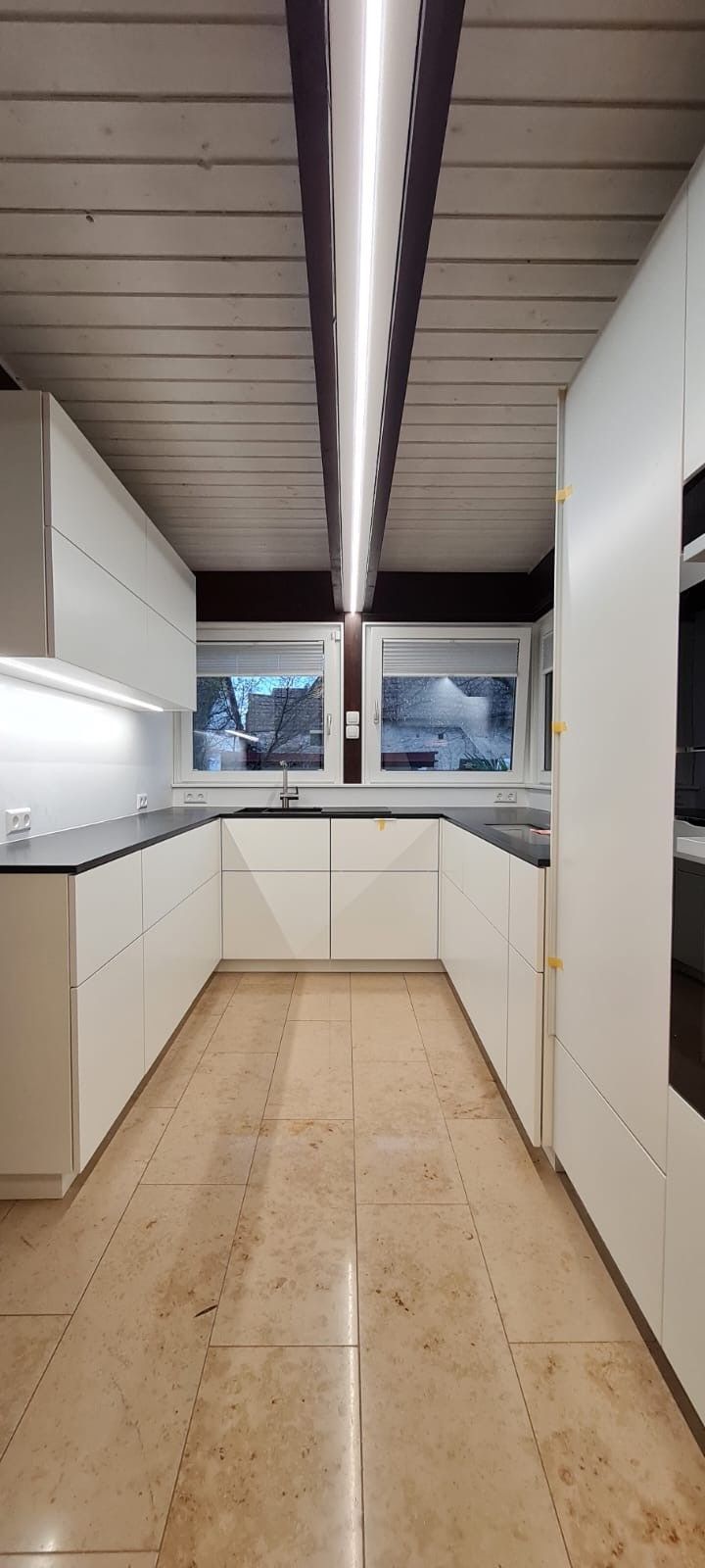 Eine leere Küche mit weißen Schränken und gefliestem Boden.