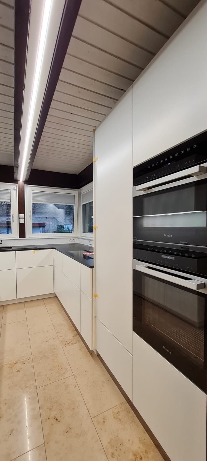 Eine Küche mit weißen Schränken und Geräten aus Edelstahl.