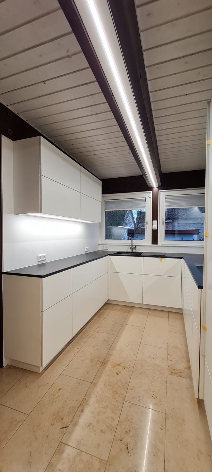 Eine Küche mit weißen Schränken und einer schwarzen Arbeitsplatte.