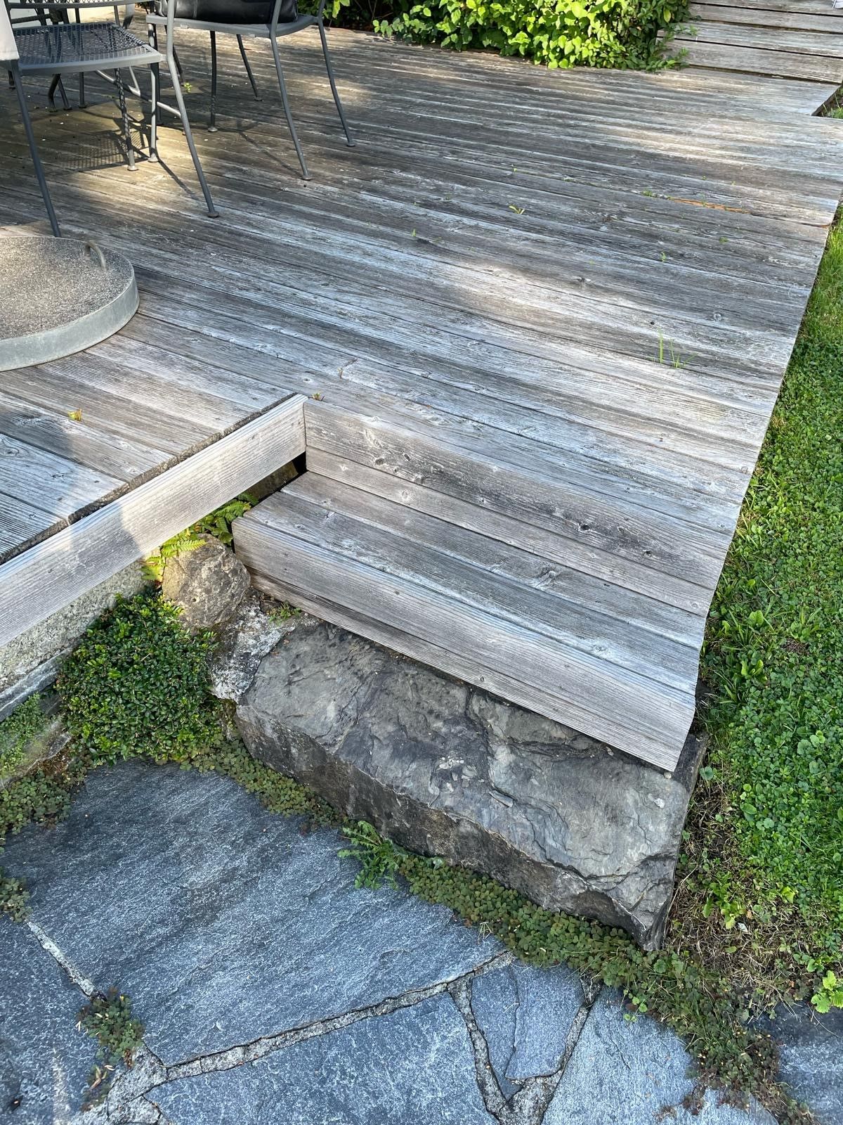 Ein Holzdeck mit hinaufführenden Treppen und einem Steinweg.