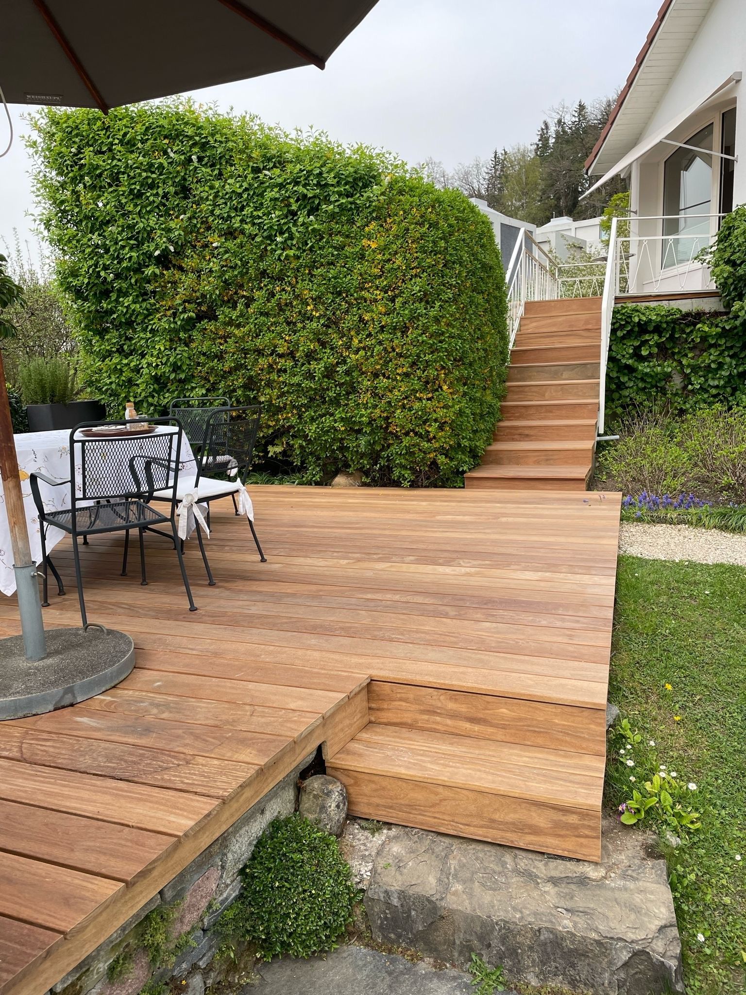 Eine Holzterrasse mit Treppen, die zu einem Haus hinaufführen.