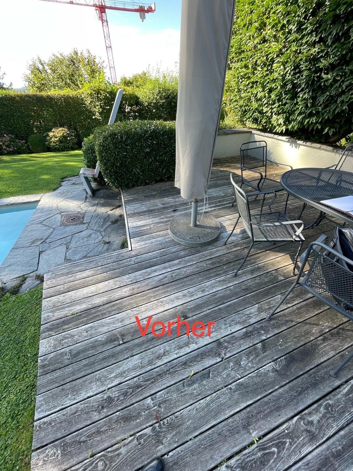 Eine Holzterrasse mit Tisch und Stühlen neben einem Pool.