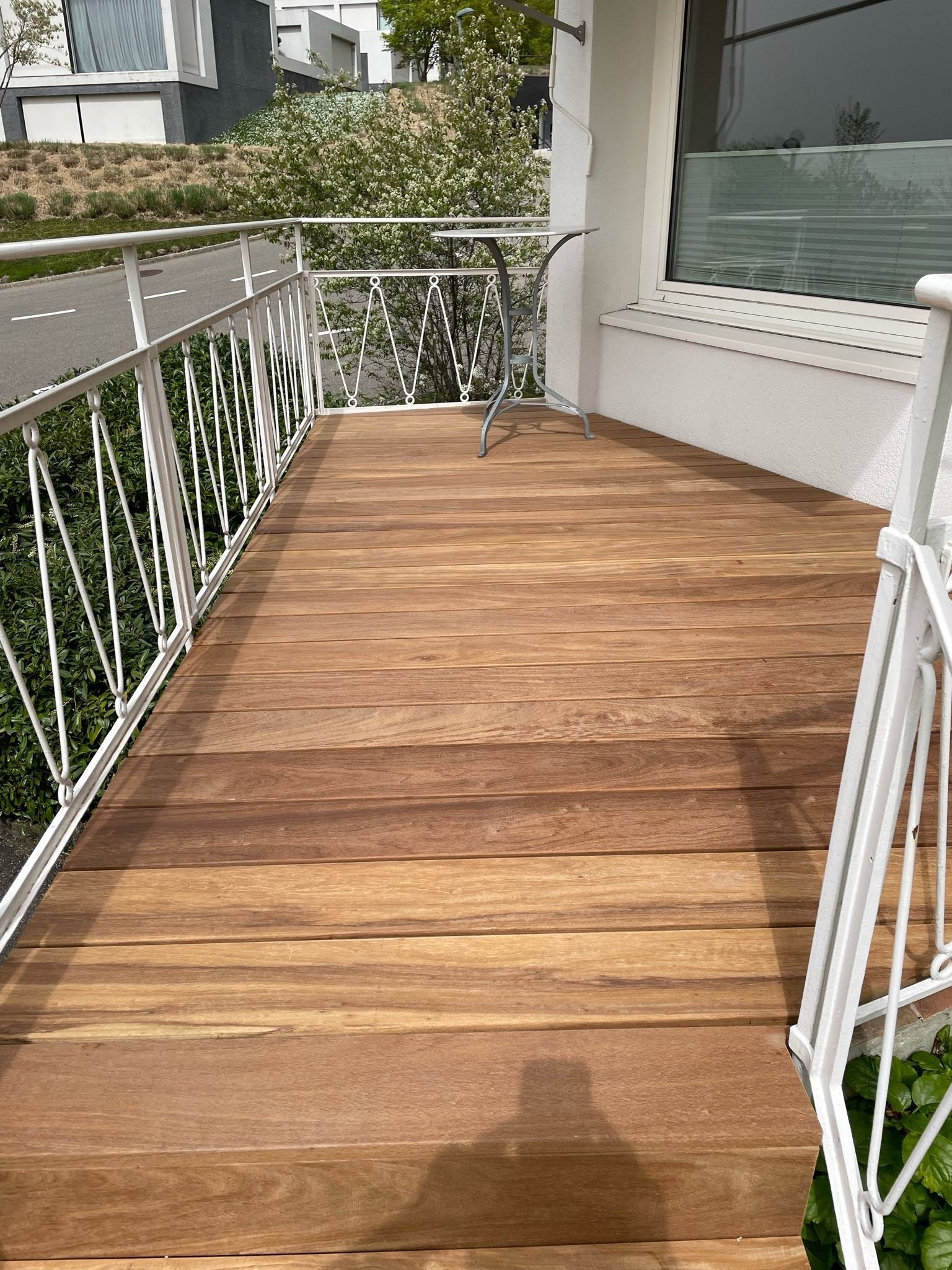 Ein Balkon mit Holzdeck und weißem Geländer.