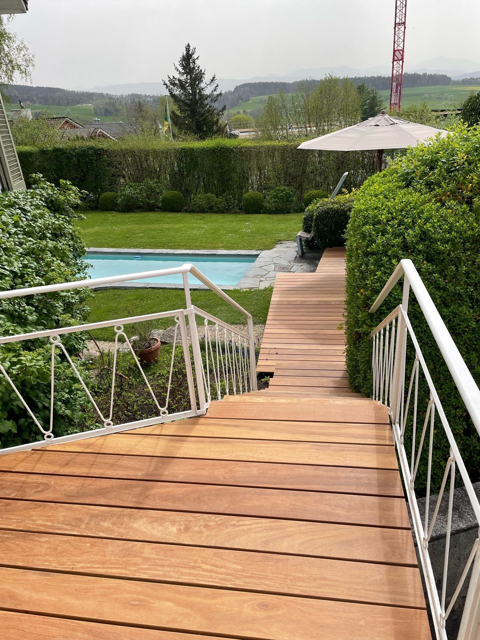 Ein Holzsteg, der zu einem Swimmingpool in einem Hinterhof führt.