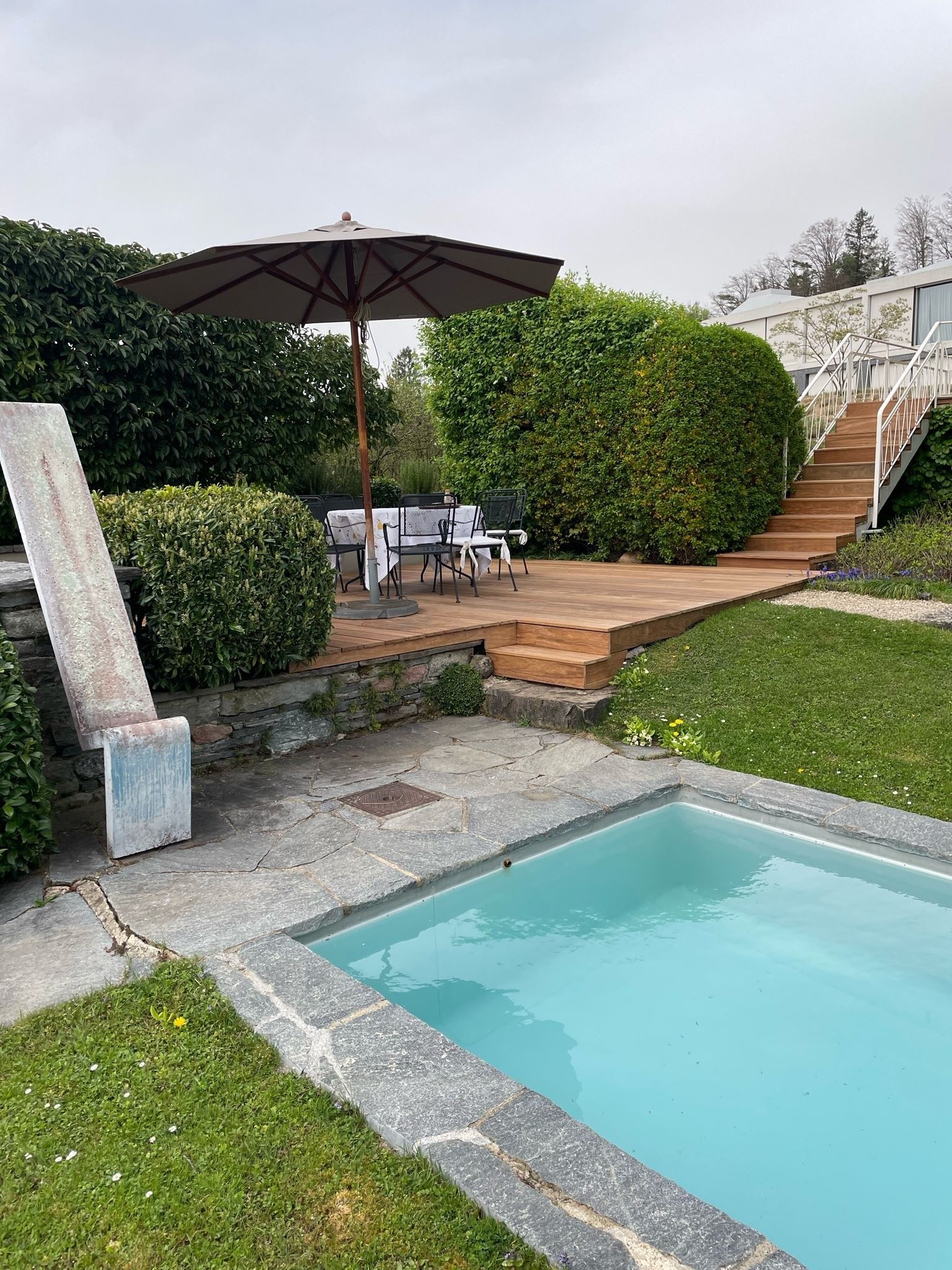 Im Hinterhof gibt es einen Swimmingpool mit einem Tisch und Stühlen unter einem Sonnenschirm.