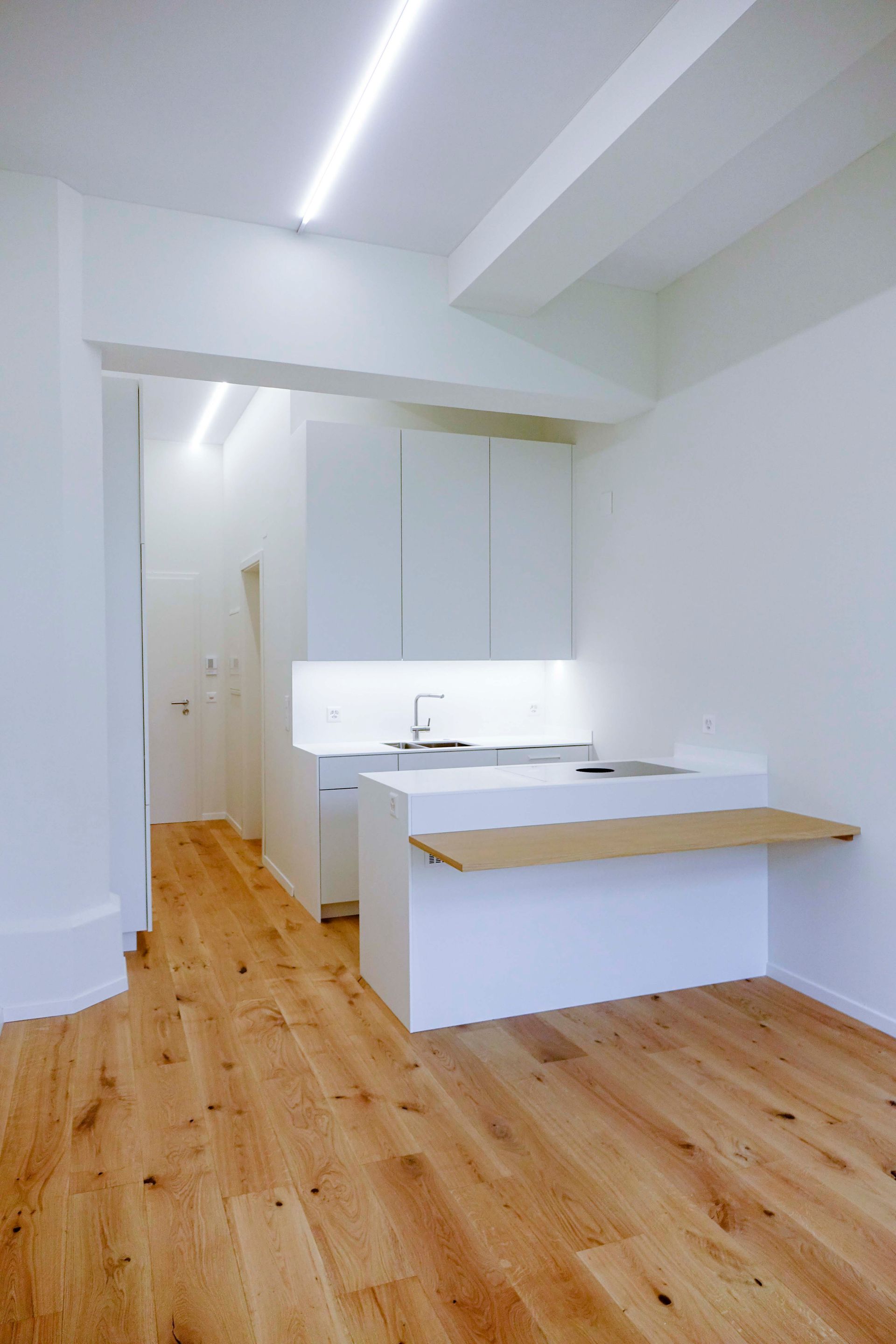 Eine Küche mit Holzboden und weißen Schränken.