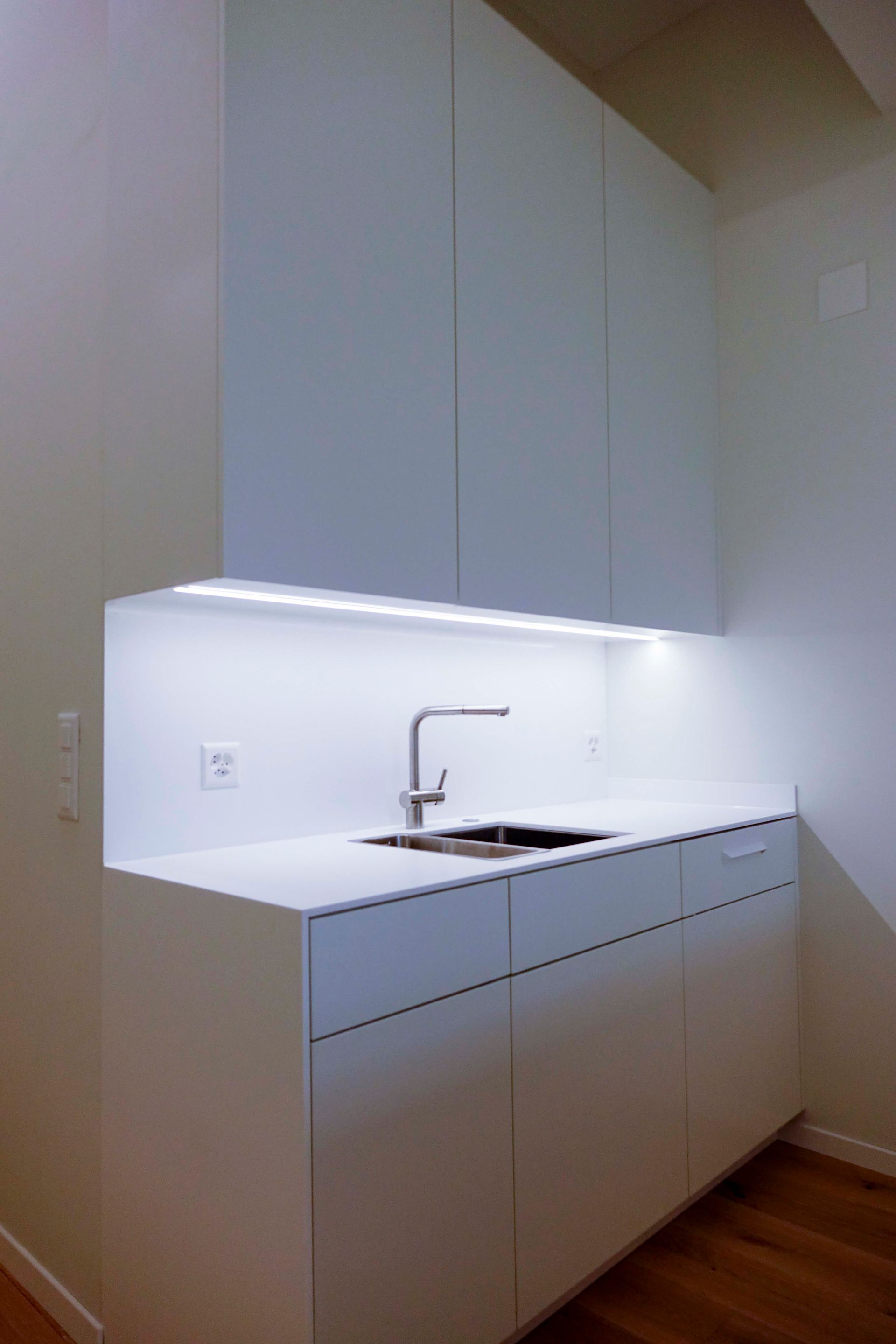 Eine Küche mit weißen Schränken und einer Spüle.