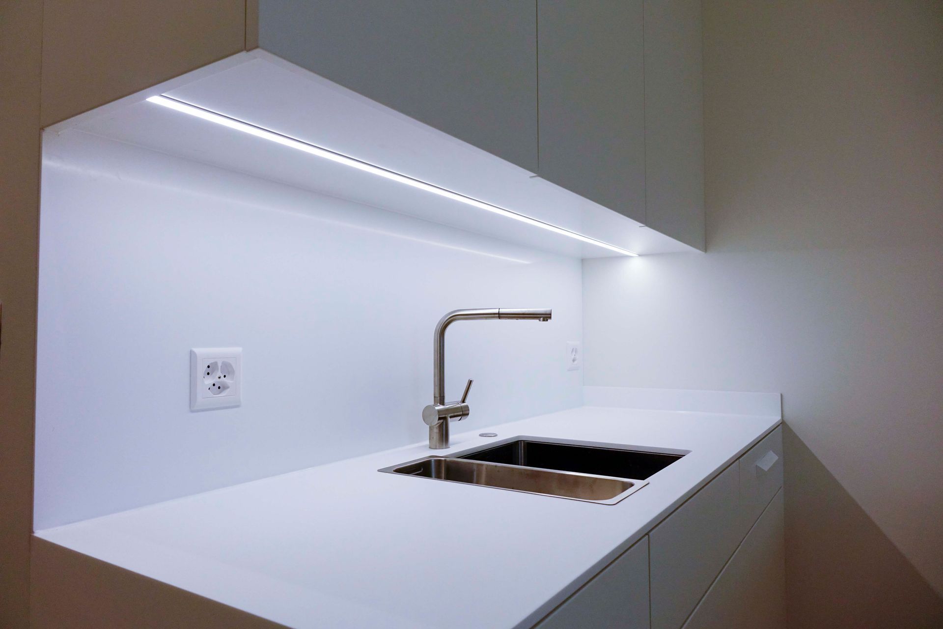 Eine Küche mit Spüle und Wasserhahn unter einer Lampe.