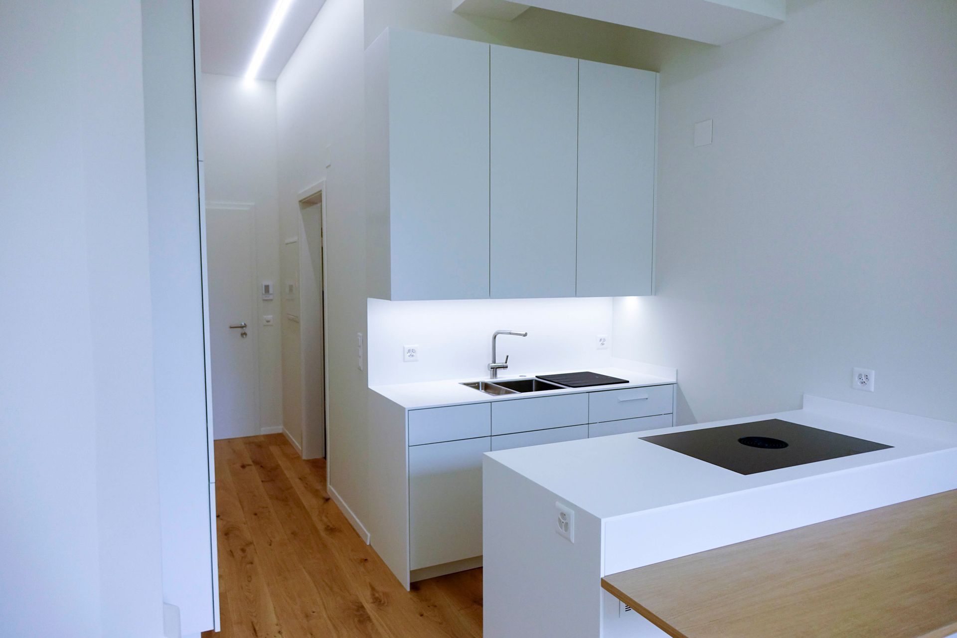 Eine Küche mit weißen Schränken, einer Spüle und einem Herd mit Backofen.