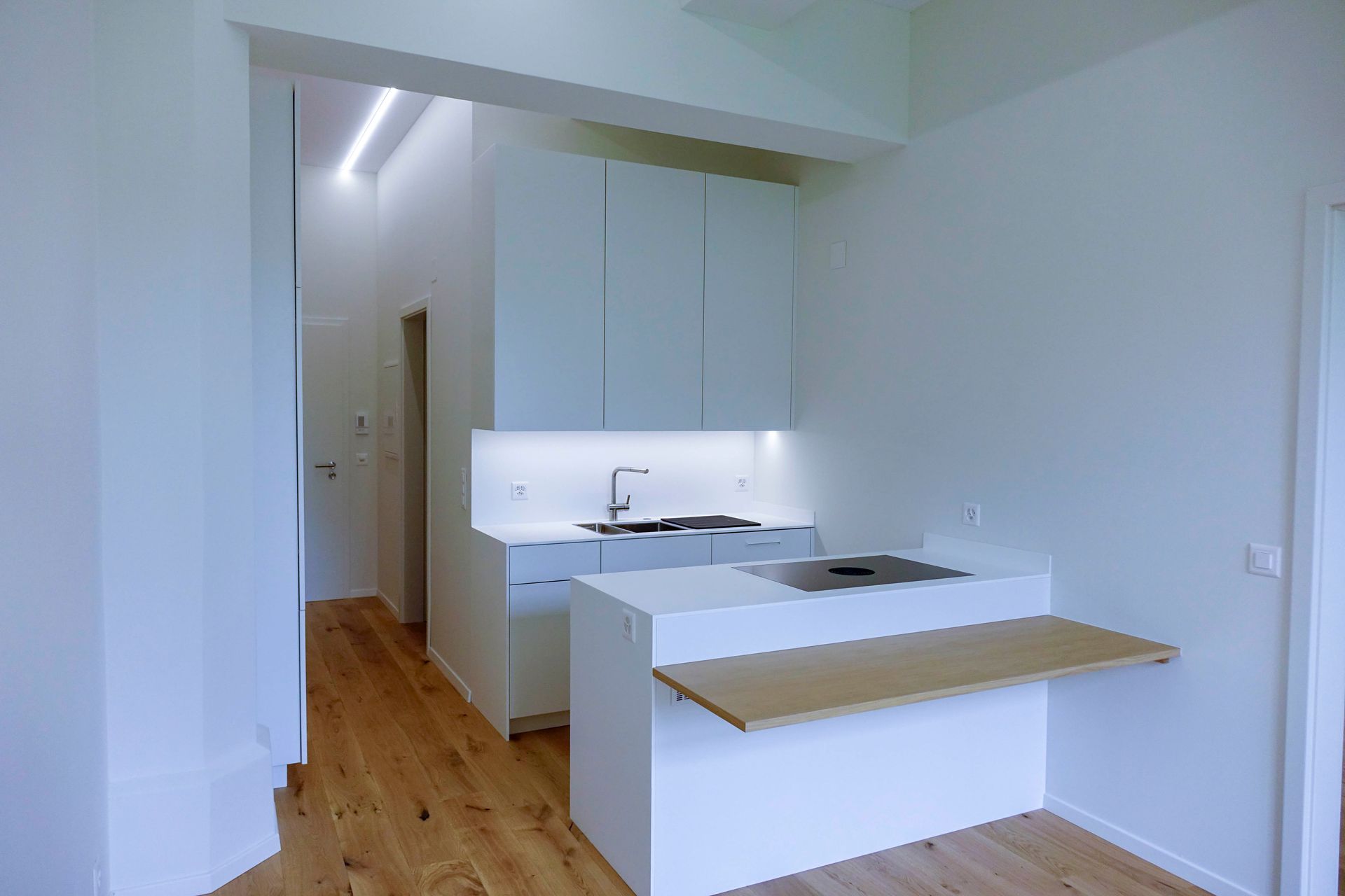 Eine leere Küche mit weißen Schränken und Holzböden