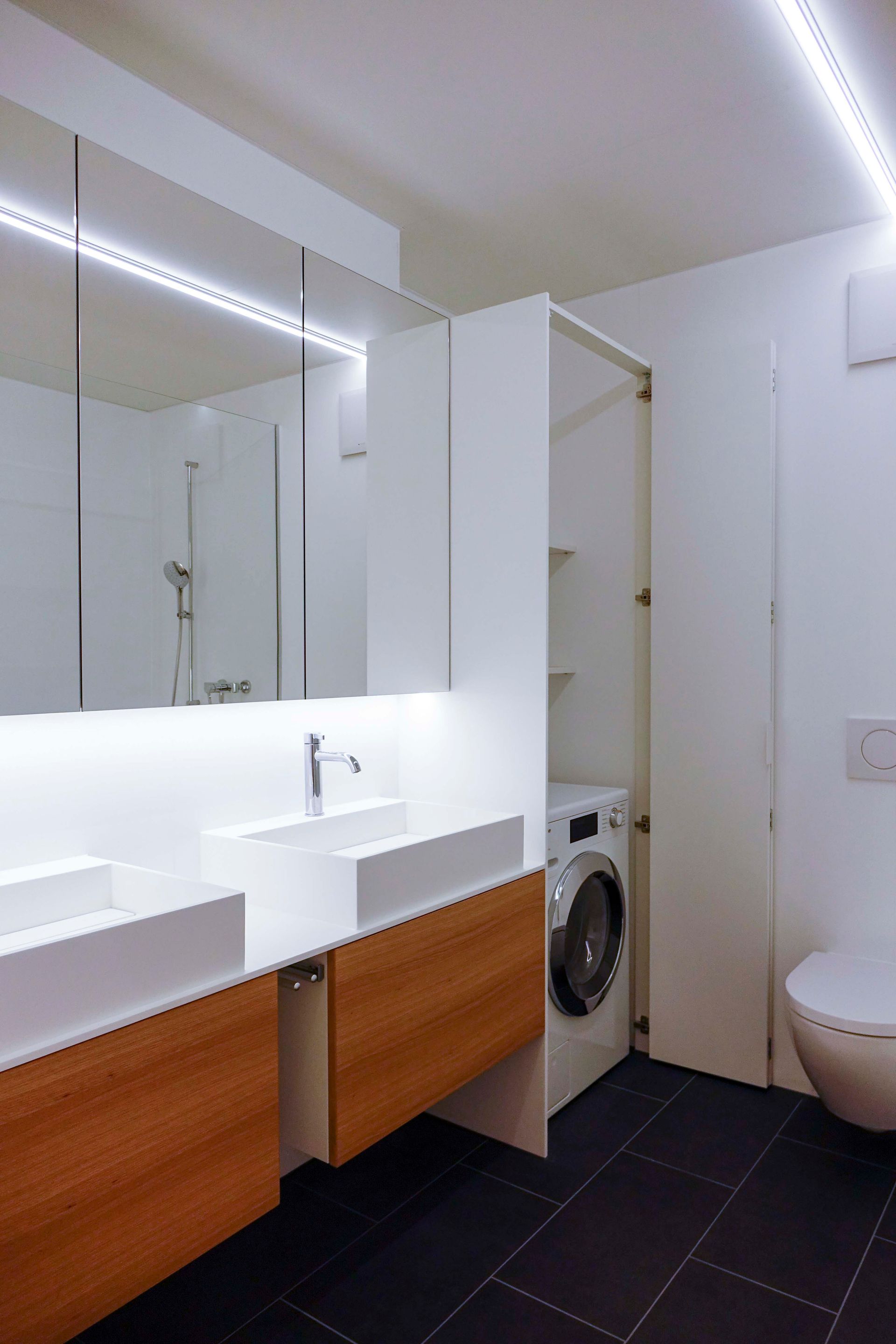 Ein Badezimmer mit zwei Waschbecken sowie einer Waschmaschine und einem Trockner