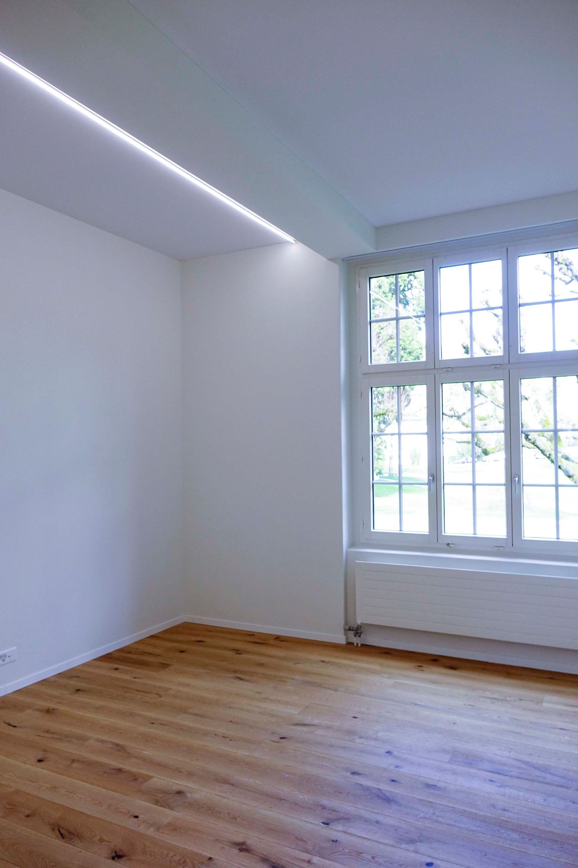 Ein leerer Raum mit Holzboden und Fenster.