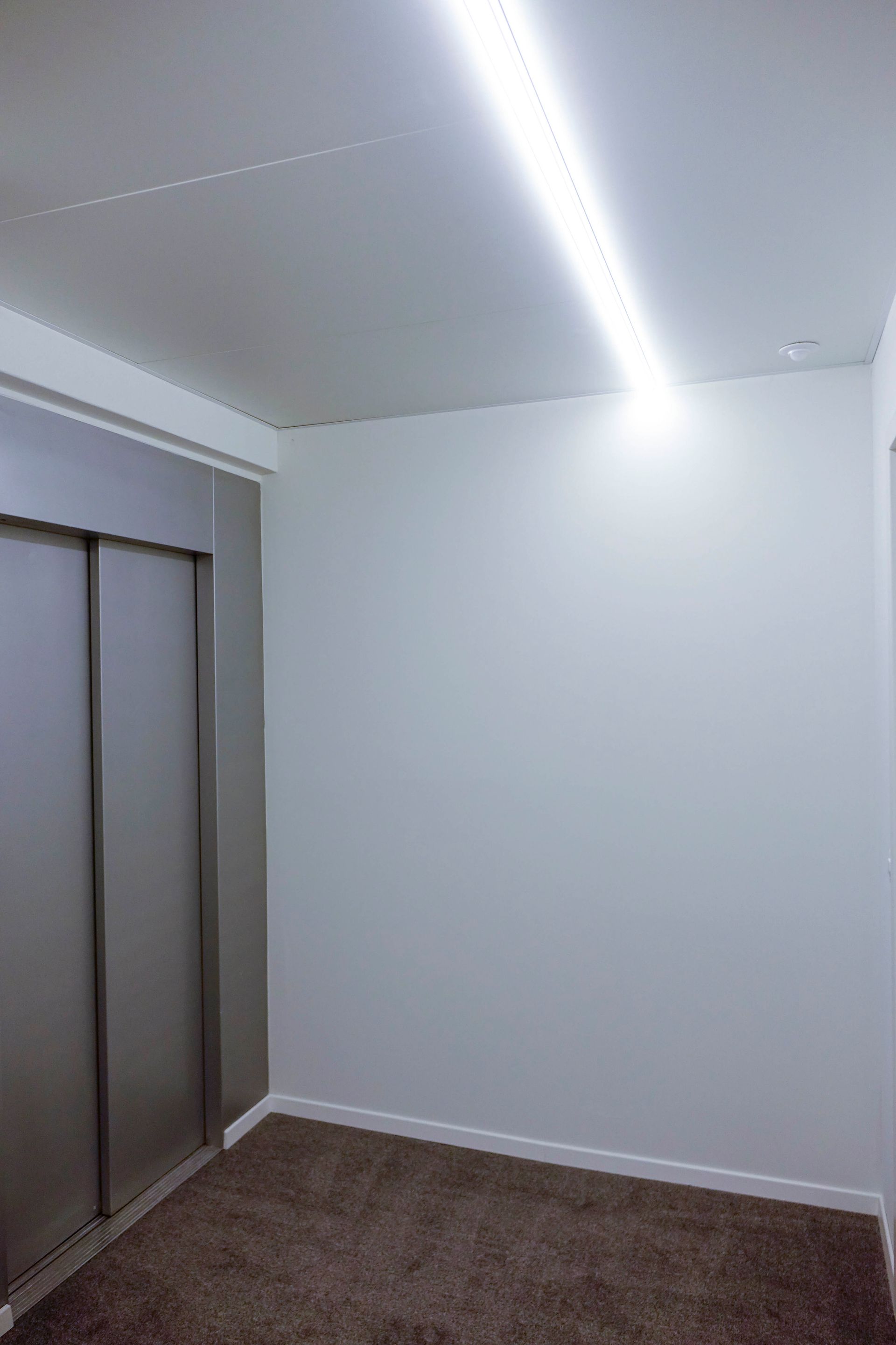 Ein leerer Raum mit einer Glasschiebetür und einer Lampe an der Decke.