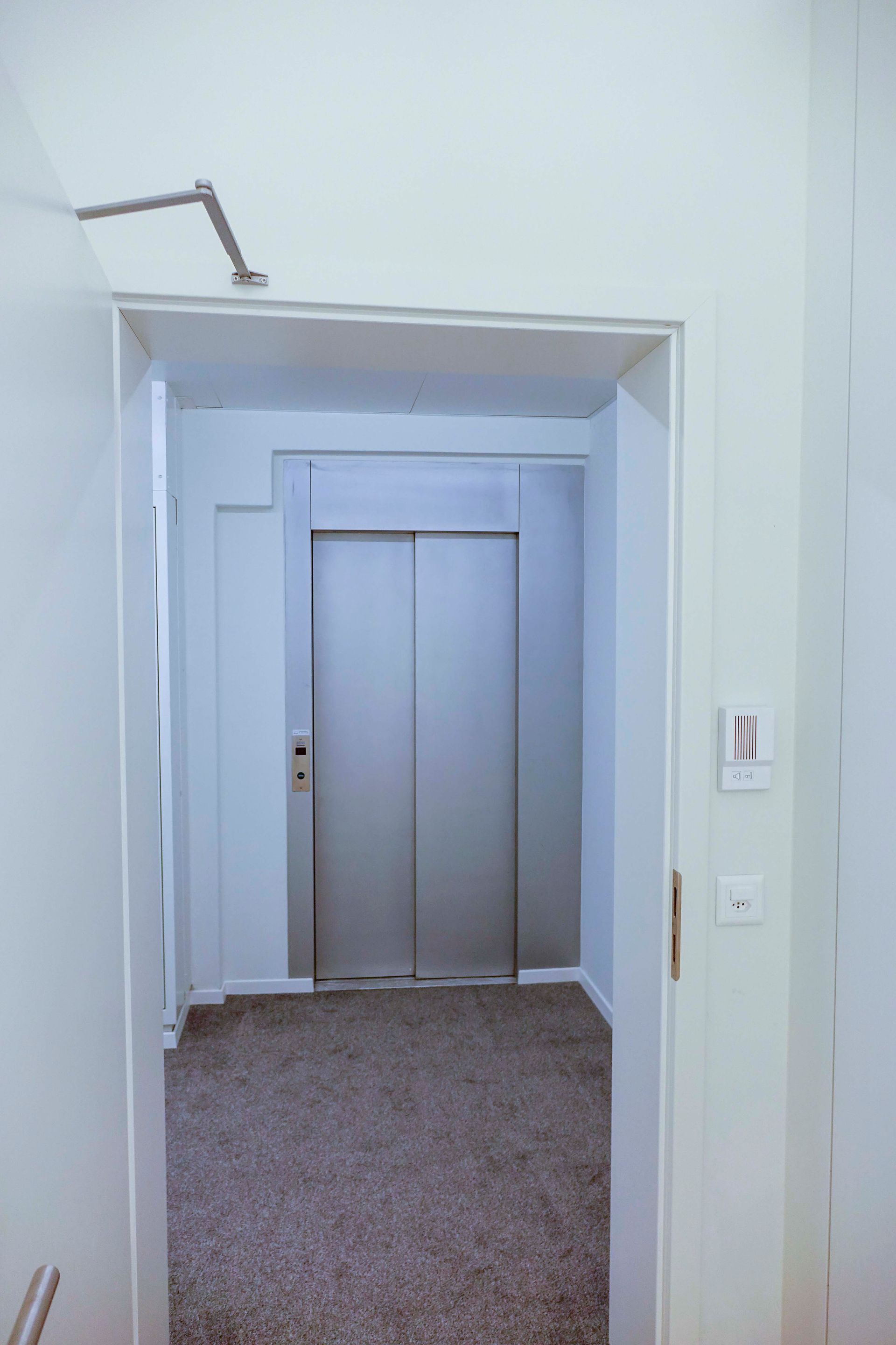 Ein Flur mit einer Tür, die zu einem Aufzug führt.