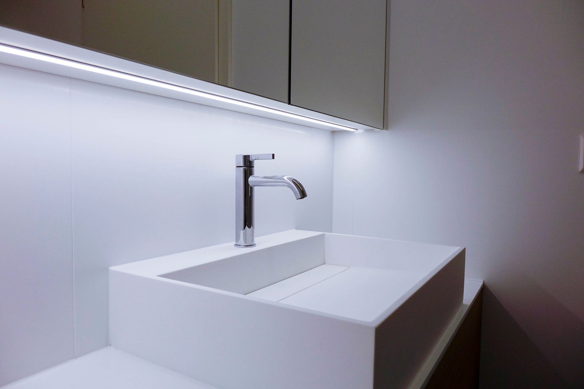 Ein Waschbecken mit Wasserhahn und Spiegel.