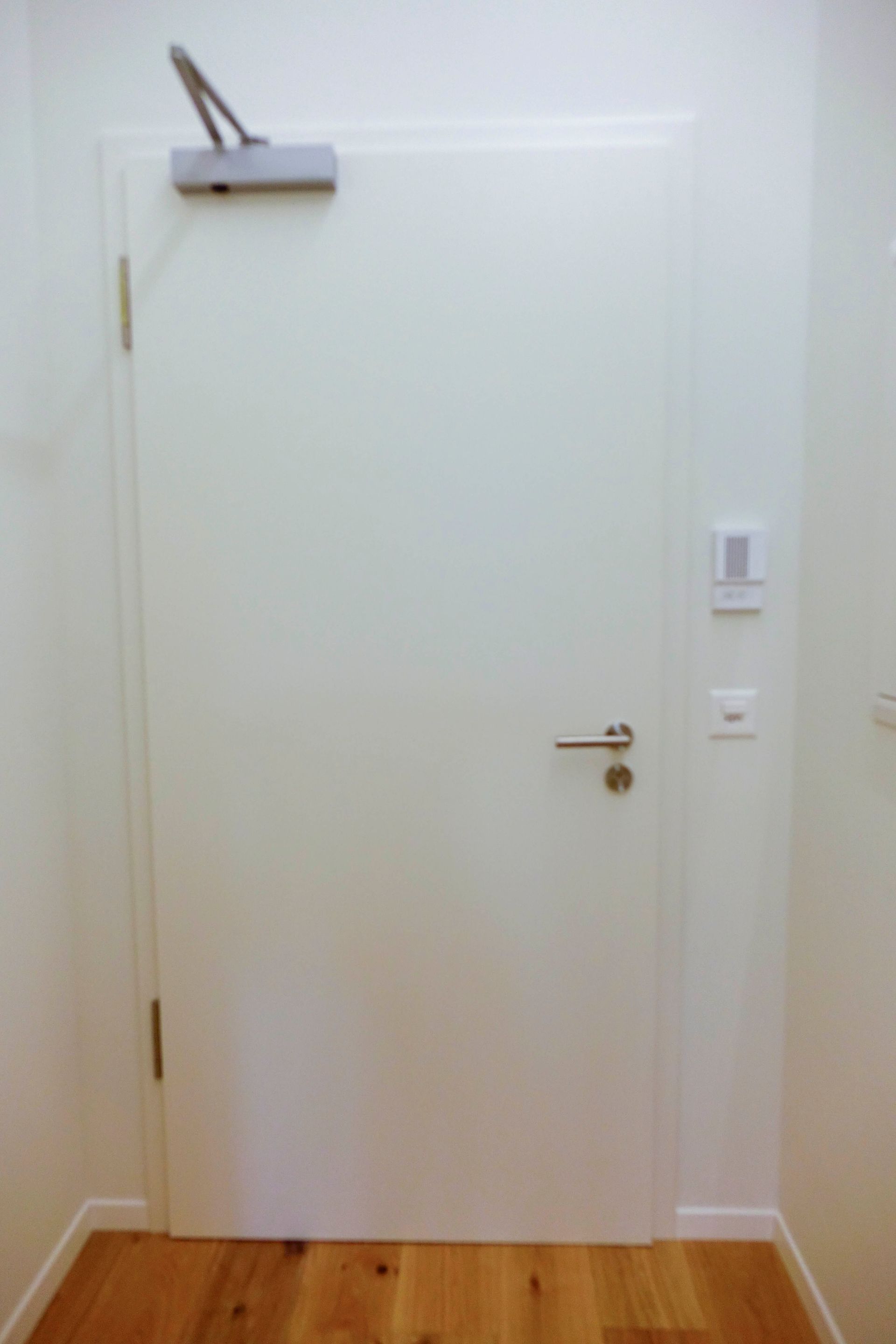 Eine weiße Tür mit Holzboden in einem Flur.