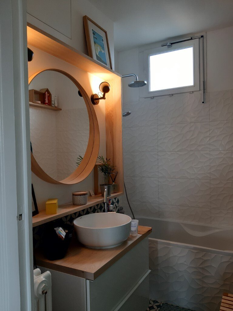 Eclairage par deux spots au-dessus d'un miroir rond dans une salle de bains