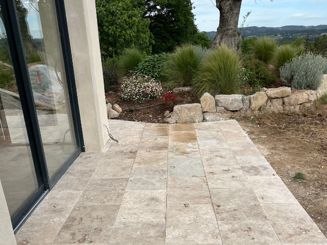 Un patio avec une porte coulissante en verre et un arbre en arrière-plan.